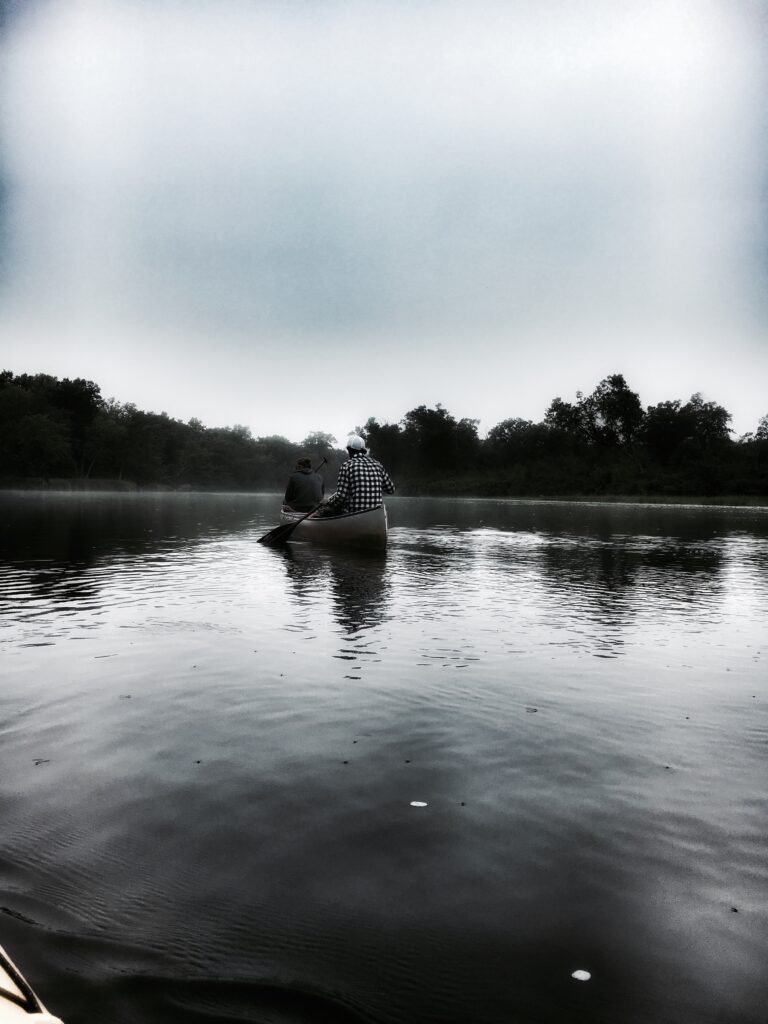 Two travelers in a canoe paddling on the St. Croix Scenic Riverway in fog 