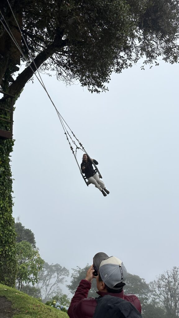 Traveler swinging on the end of the world swing located at La Casa del Árbol in Banos, Ecuador